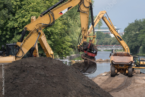 EXCAVATORS AND ARTICULATED HAULER - Construction machines are working on the river
