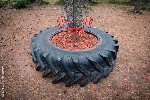 red disc golf basket inside of a tractor tire