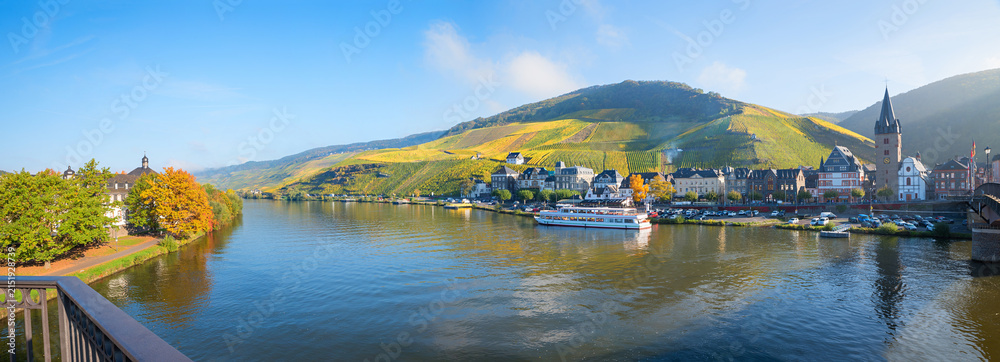 Naklejka premium view from bridge to Moselle river with ship, tourist resort Bernkastel and vineyards in autumn