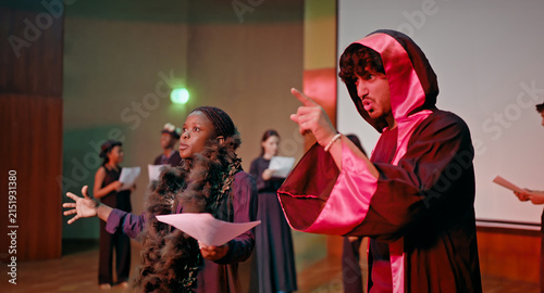 Indian young adult gen z lady female male man wear stage dress hold paper do casual scene studio hall happy boy girl read talk speak new story lines learn next drama play enjoy day time campus place