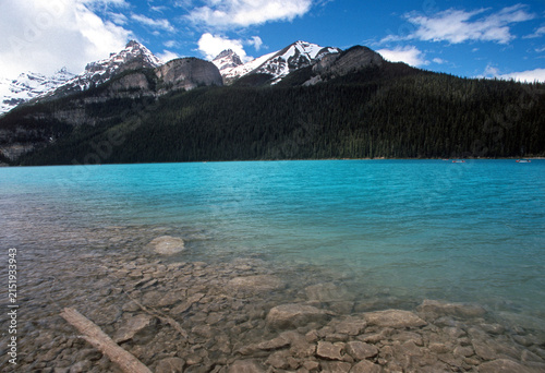 Clear turquoise waters and rocky shoreline of Lake Louise with Mount Victoria in the background