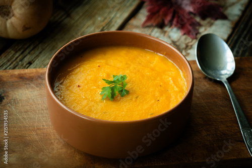 Pumpkin puree soup adorned with a parsley. Seasonal autumn meal, vegetable cream soup. Thanksgiving dinner in rustic style