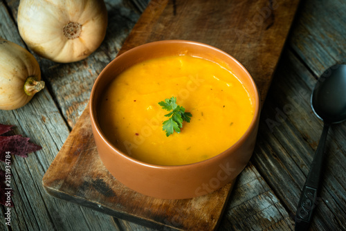 Creamy pumpkin soup topped with a parsley sprig. Thanksgiving meal.