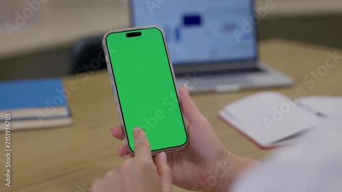 Woman Using Smartphone with Green Screen Chroma Key at Her Desk in Office. Woman Using Mobile Phone, Browsing Internet, Social Networks, Financial Reports