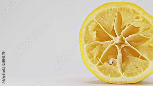 Close up slider shot of juicy squeezed lemon half on clean white background