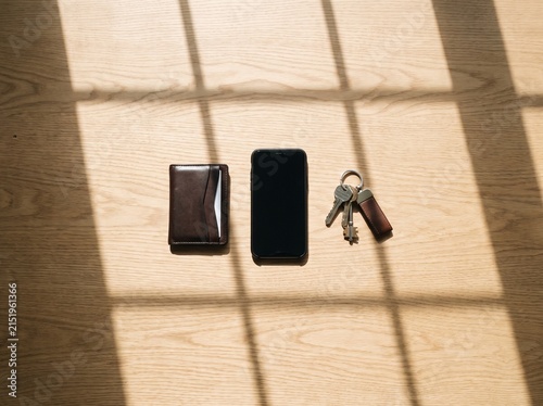 Everyday essentials laid out on a wooden floor with sunlight casting shadows.