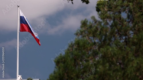 Russian national flag waving on flagpole against blue sky
