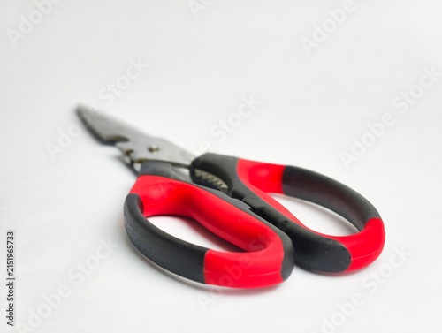 Close-up perspective of red and black ergonomic handles on stainless steel kitchen shears, isolated on a white background with shallow depth of field.