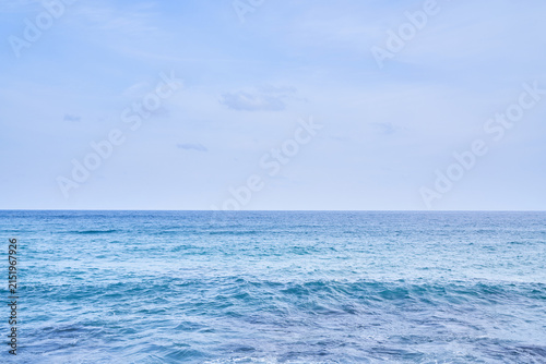 A serene coastal landscape with a clear horizon separating gentle turquoise waves and a soft pastel sky. This minimalist maritime scenery provides expansive empty space for seasonal design layouts.