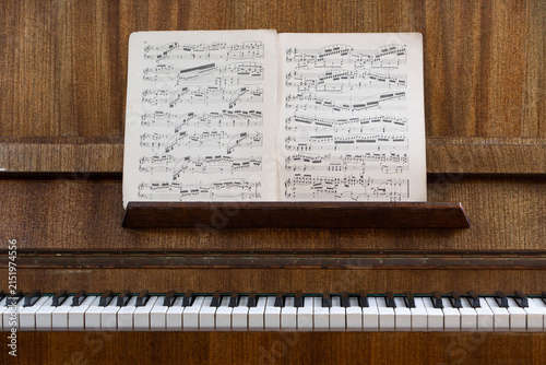 Vintage upright piano with classical sheet music on the music stand, showcasing timeless musical heritage, acoustic instrument, traditional composition and public domain music.