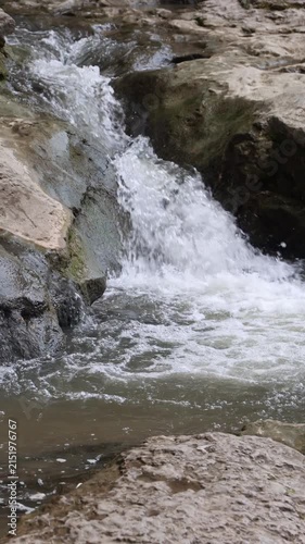 Fresh river water rushing down rocky mountain cascade. Vertical