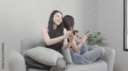 Two Asian Women Having a Fun Conversation While Using Smartphones
