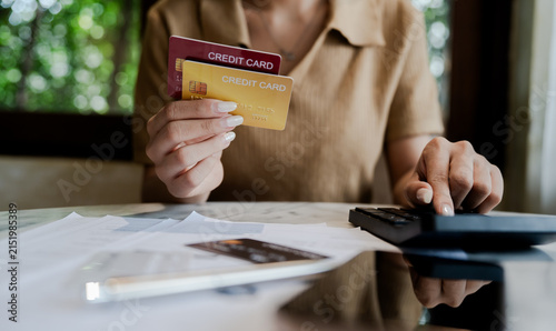 Woman holding credit cards while calculating expenses and reviewing bills, representing credit debt, personal finance, financial stress, and money management.