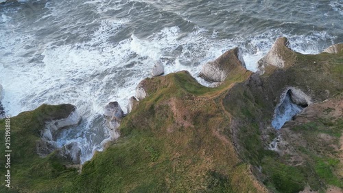 Drone aerial panoramic shot flying right along white chalk cliffs and sea cave
