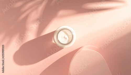 Open Glass Jar of Cream Resting on Soft Pink Surface in Warm Sunlight