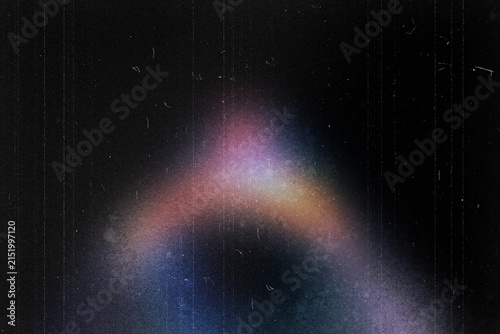 Vintage film grain texture with light leak, retro analog overlay with dust and scratches, colorful light flare on black background