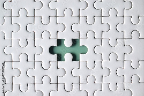 Принти на полотні A direct macro top view centered on a single missing piece hole within a white jigsaw puzzle grid, exposing the solid light green surface underneath