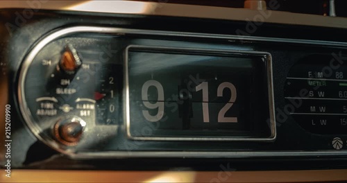Timelapse of vintage flip clock radio changing numbers with dynamic sunlight streak