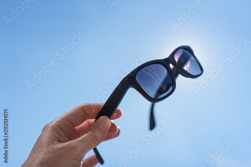Hand holding smart glasses outside in bright sunshine