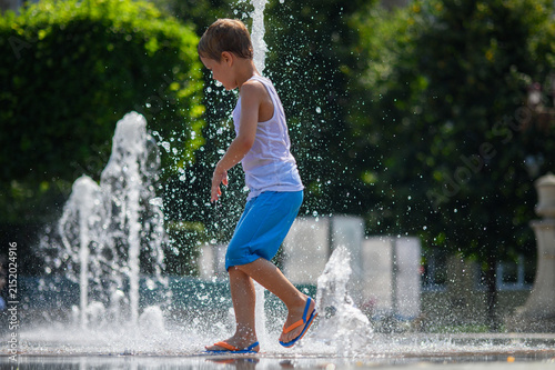 Happy Little Boys Playing in Splash Fountain on Hot Summer Day in City Park