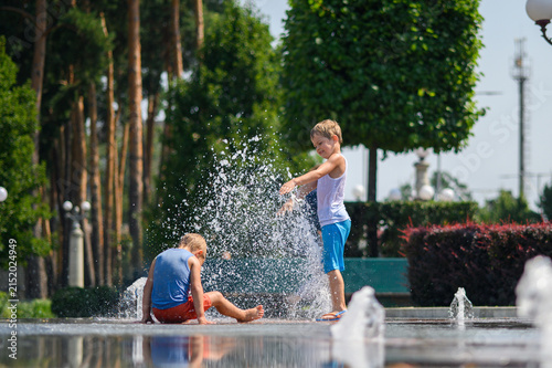 Happy Brothers Playing in Splash Fountain on Sunny Summer Day in City Park