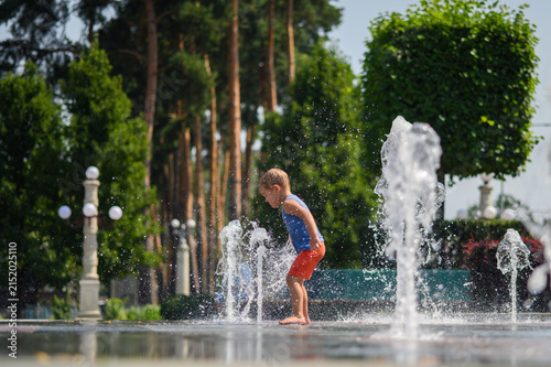 Happy Little Boys Playing in Splash Fountain on Hot Summer Day in City Park