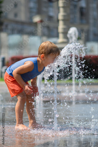 Happy Little Boys Playing in Splash Fountain on Hot Summer Day in City Park