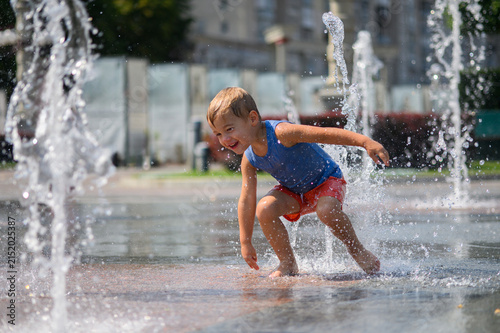 Happy Little Boys Playing in Splash Fountain on Hot Summer Day in City Park