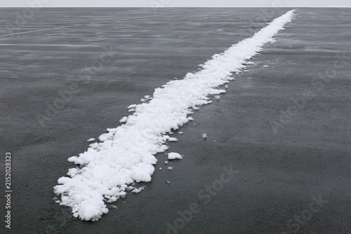 A narrow line of white snow stretches across a dark, frozen expanse