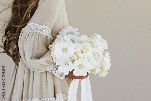 Bride in boho linen wedding dress holding white bridal bouquet.