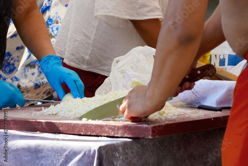 Food preparation process when multiple hands cutting onions during street parade.