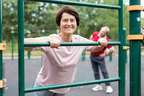Konstfotografi elderly woman performs exercises on horizontal bars in an outdoor sports area