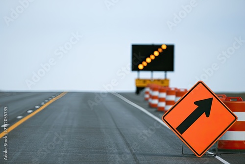 Road construction ahead with orange barrels, warning signs, and flashing arrow sign