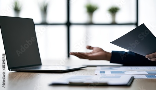 Person gestures toward laptop with financial charts
