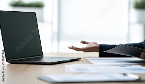 Person gesturing at laptop and tablet during a business meeting