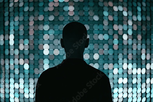 Silhouette of a person facing a shimmering, bokeh-filled digital wall of lights