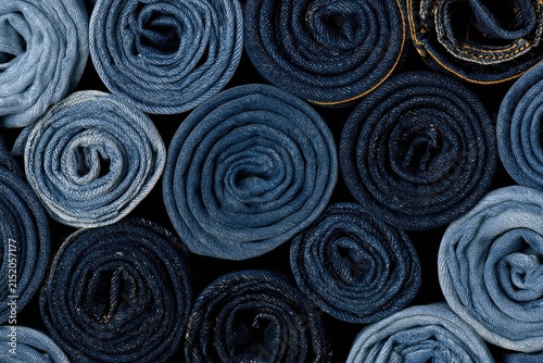 A collection of rolled denim fabric in various shades of blue