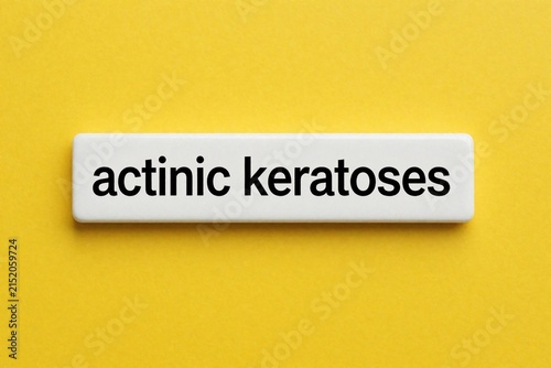 White tile displays actinic keratoses text against bright yellow background. Simple modern graphic for medical education or skin health awareness topics.