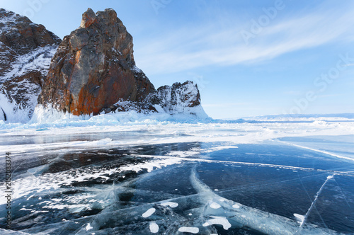 Scenic winter landscape of frozen Baikal Lake on sunny February day. Popular landmark on Olkhon Island is Cape Khoboy. Clear blue ice and icy crusts on rocks attract tourists. Winter ice travels 