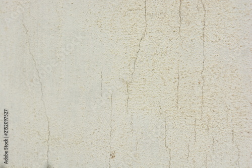 Construction and renovation work, plastering load-bearing street walls in sunlight. The white walls are coated with rough street primer with long micro-cracks throughout the surface and background.