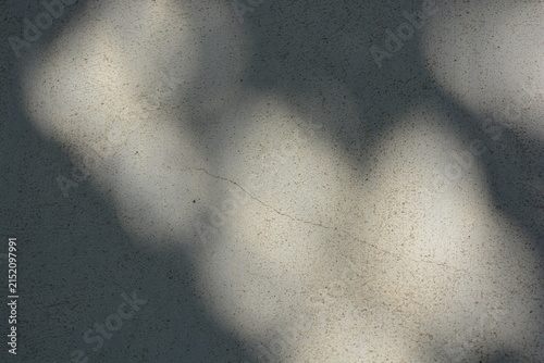 Construction and renovation work, plastering load-bearing street walls in sunlight. The white walls are coated with rough street primer with long micro-cracks throughout the surface and background.
