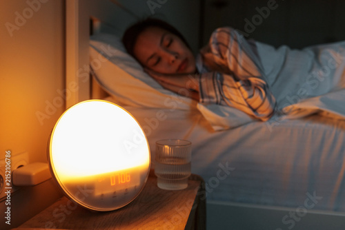 Canvas Print Selective focus on sunrise simulation artificial dawn alarm clock standing on be
