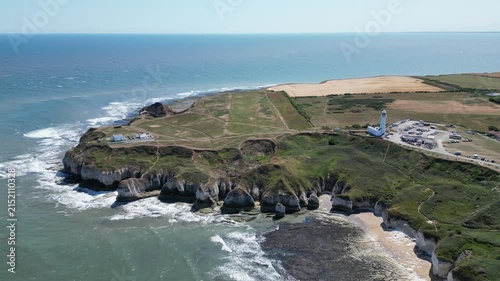 Wide aerial pull away view of Flamborough Head Lighthouse and dramatic cliffs, England