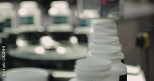Food supplement plastic bottles motion under photoelectric sensor at factory storehouse closeup. Innovative system of vitamin manufacturing and distribution