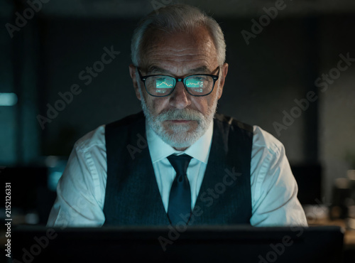A middle-aged respectable man wearing glasses watches the monitor, the work of a trader, an editor.