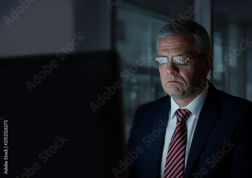 A middle-aged respectable man wearing glasses watches the monitor, the work of a trader, an editor.