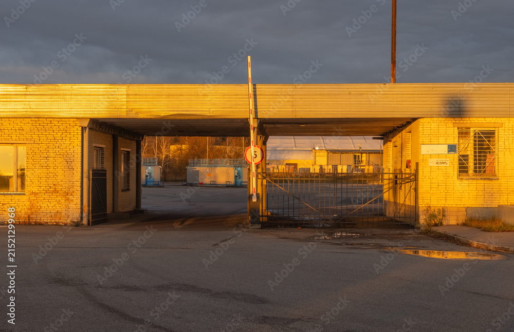 Naklejka premium Abandoned industrial entrance bathed in warm low sunlight during overcast evening