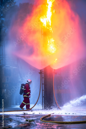 Firefighter wearing protective gear using a hose to extinguish a fire outside a building