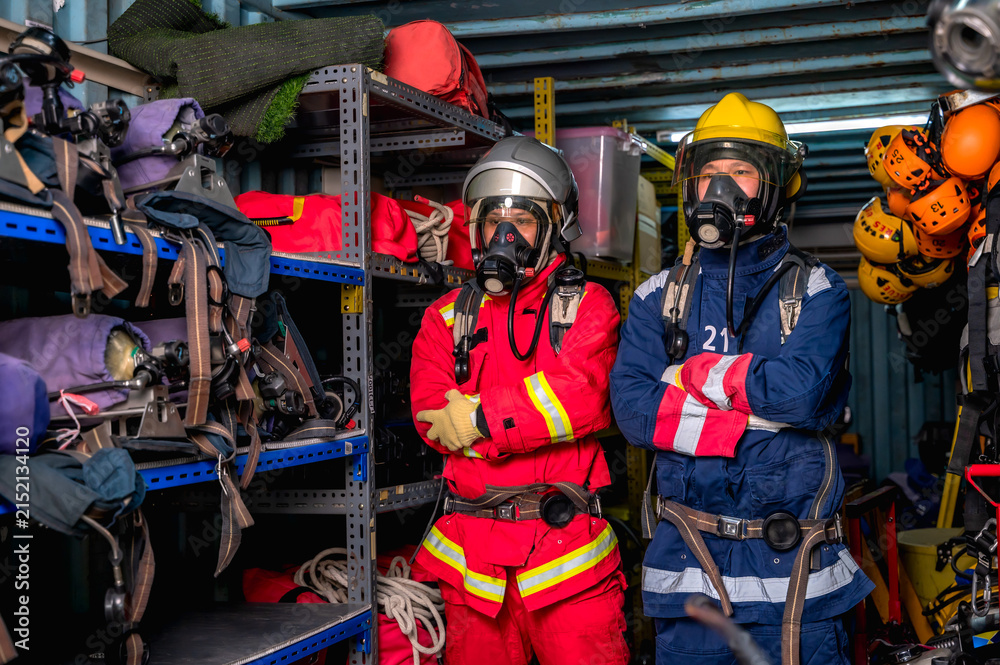 Fototapeta premium Brave male firefighters in full protective gear, helmet, and smoke mask respirator, fully equipped and standing ready to deploy for a dangerous emergency response mission