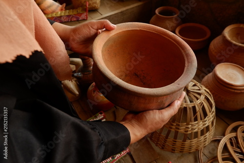 Visitor holding traditional clay pot while choosing handcrafted ceramics at market